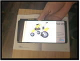 Augmented reality video of 3 chocks in a tricycle showed in a cellphone when pointing an image on the workbook.